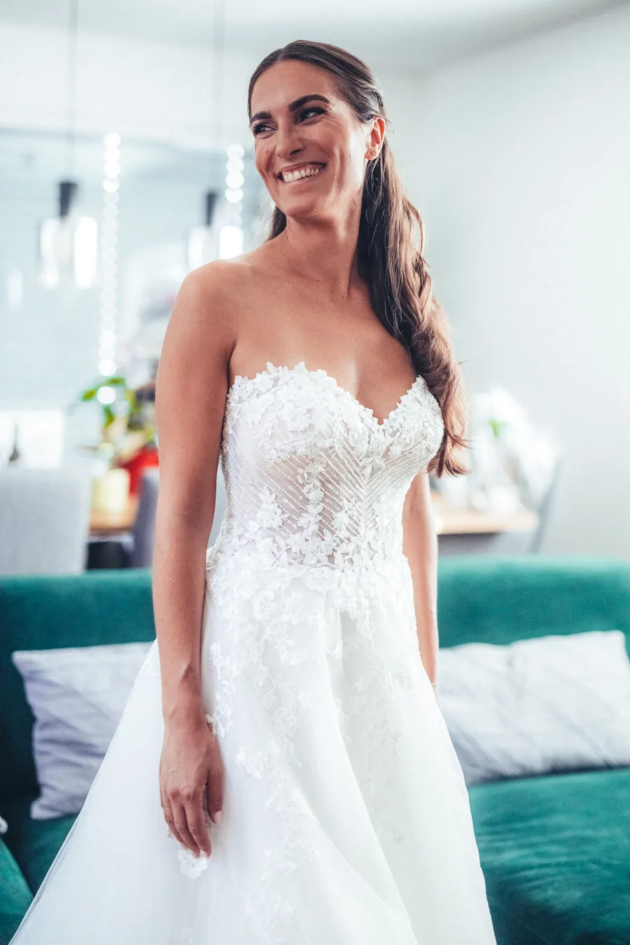 Braut im Spitzenkleid lächelt beim Getting Ready