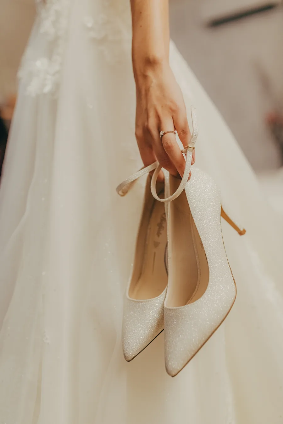 Braut trägt ihre Schuhe in der Hand, Detail vor dem Kleid