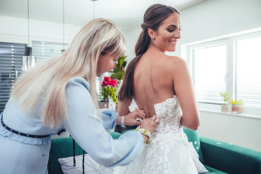 Trauzeugin schnürt das Brautkleid vor der Zeremonie