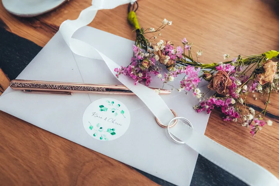 Papeterie, Eheringe und Trockenblumen auf dem Holztisch